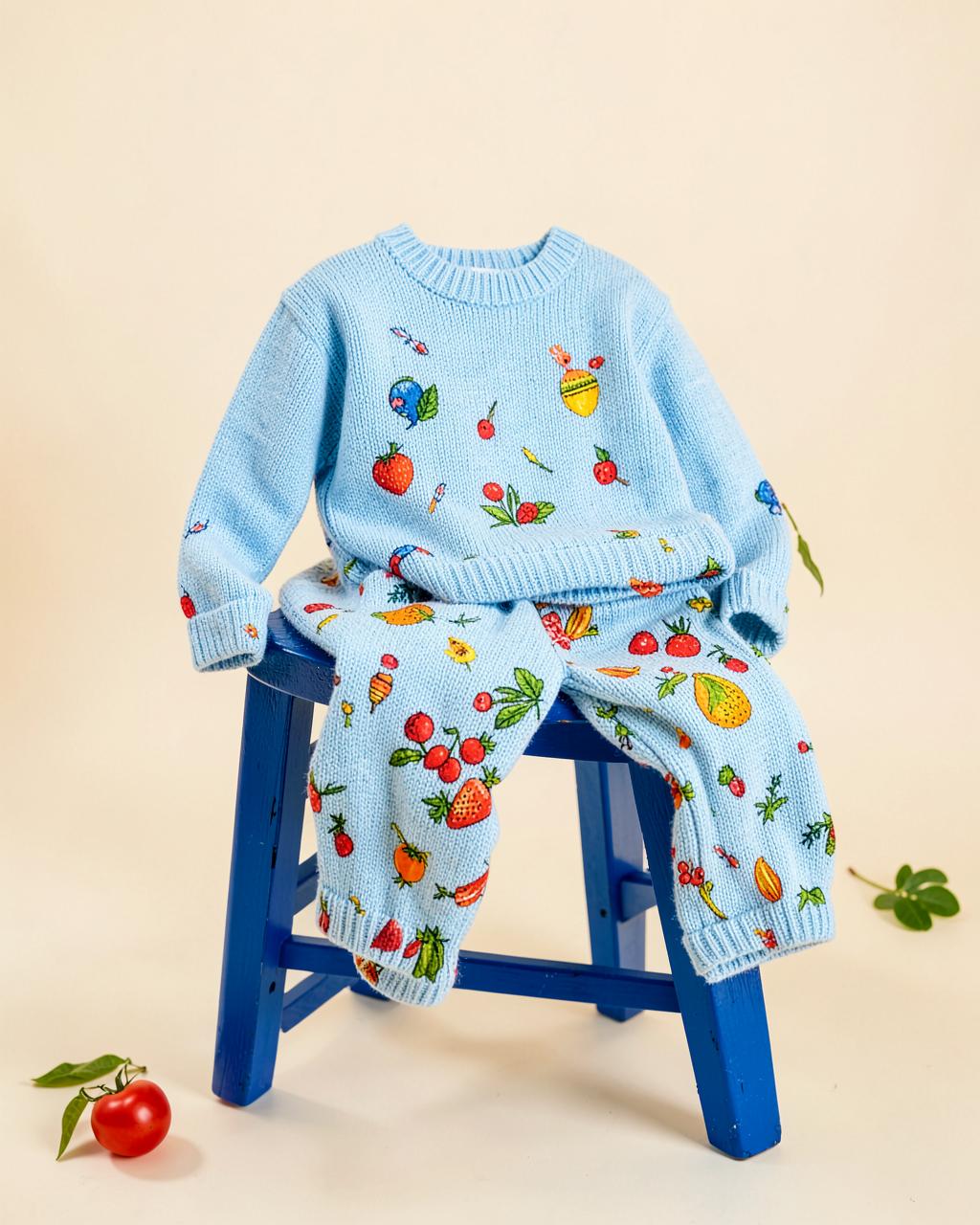 Market Day knitted jumper and trousers set, worn by a child against a colourful illustrated market backdrop